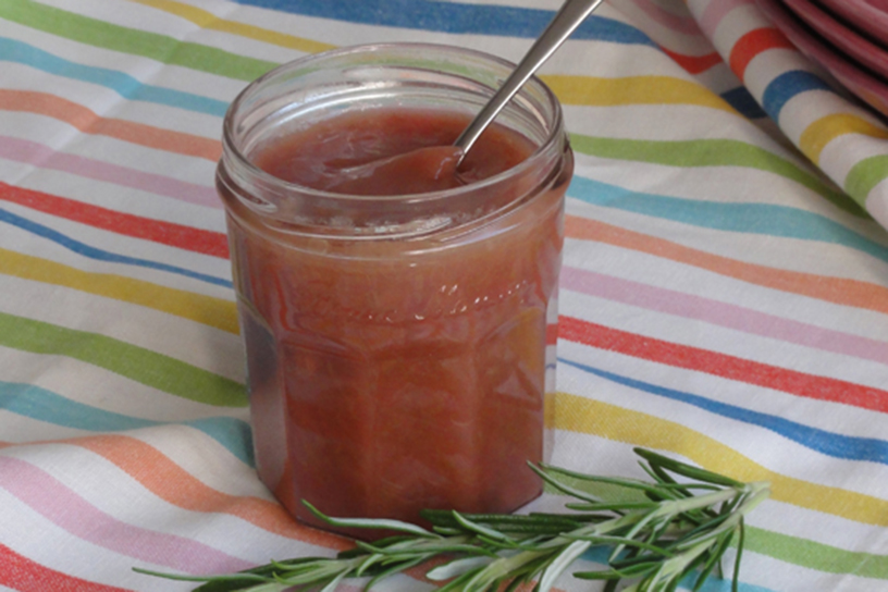 Een potje rabarberjam met een takje rozemarijn ernaast